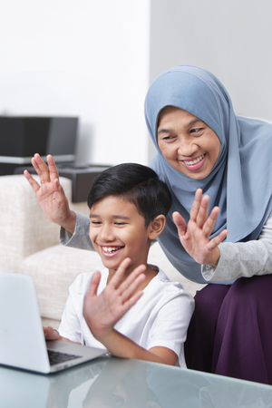 Grandmother and grandson using video cam on laptopの写真素材