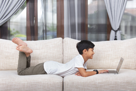 Boy lying down and using laptop