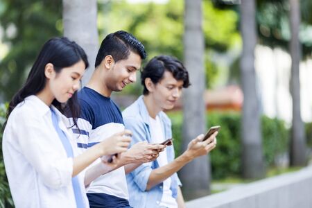 Group of friends on their mobile phoneの写真素材