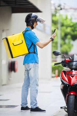 Food delivery man checking location with a mobile phoneの写真素材