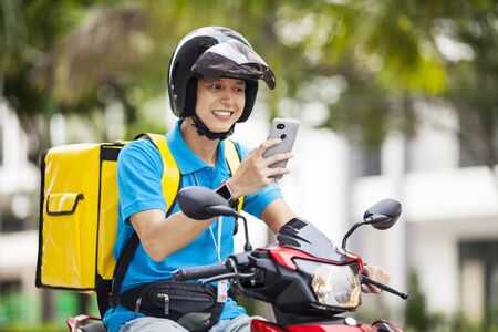 Food delivery man checking location with a mobile phoneの写真素材