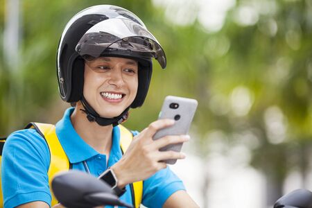 Food delivery man checking location with a mobile phoneの写真素材