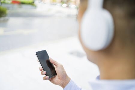 Man listening to music on headphones while using his phoneの写真素材