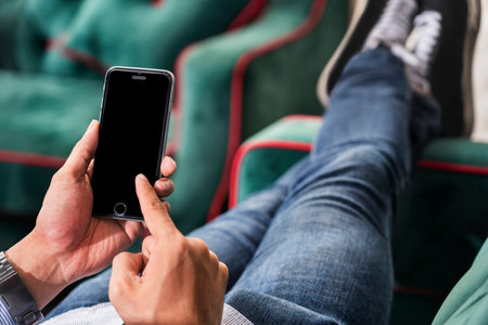 Hands using a mobile phone on a couchの写真素材