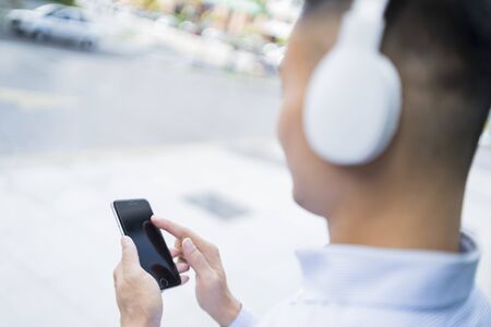 Man listening to music on headphones while using his phone