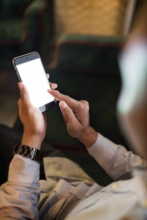 Man using a mobile phone on a couchの写真素材
