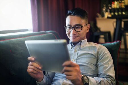 Man using a digital tablet on a couchの写真素材