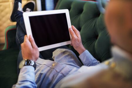 Man using a digital tablet on a couchの写真素材