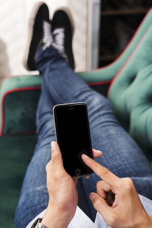 Man using a mobile phone on a couchの写真素材