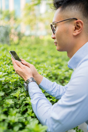 Man taking picture of plants with mobile phone
