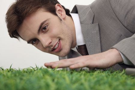 Man smiling with hand touching the tip of grass