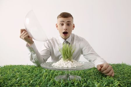 Man looking at grass on cake stand with opened mouthの写真素材