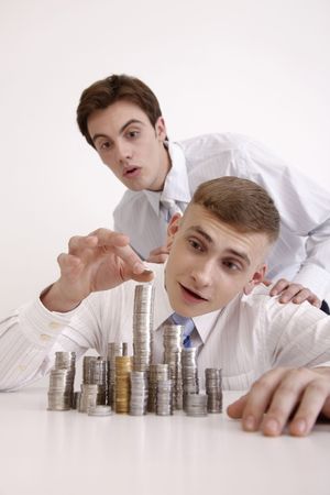 Man watching his collegue stacking coinsの写真素材