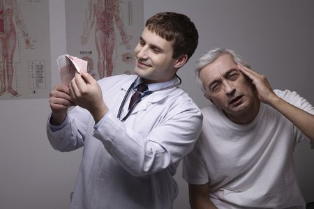 Doctor counting money, patient having headacheの写真素材