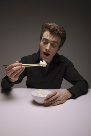 Man eating white rice with chopsticksの写真素材