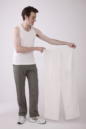 Man holding a pair of white pantsの写真素材