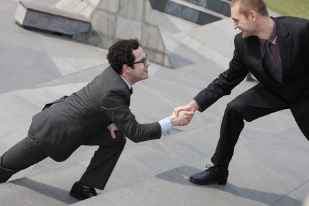 Businessman offering outstretched hand to another businessmanの写真素材