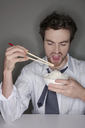 Man eating rice with chopsticksの写真素材