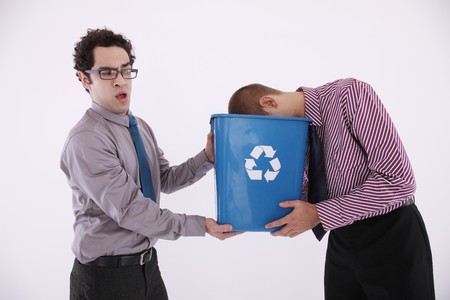 Businessman holding recycling bin, man putting his head into the binの写真素材