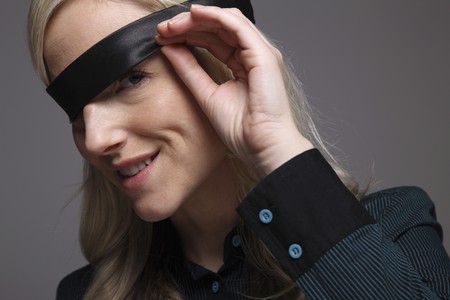 Businesswoman peeking under blindfoldの写真素材