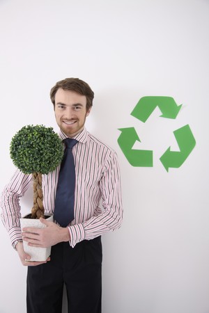 Man holding potted plant with recycling symbol at the sideの写真素材