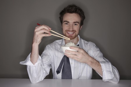 Man eating rice with chopsticksの写真素材