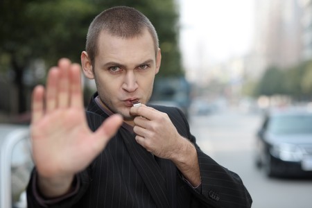 Businessman showing stop gesture while blowing whistleの写真素材