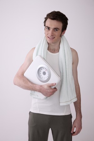 Man smiling and holding a scaleの写真素材