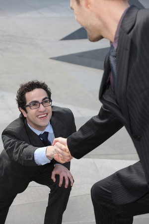 Businessman offering outstretched hand to another businessmanの写真素材