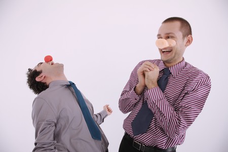 Businessman with clown's nose and pig's snout laughingの写真素材