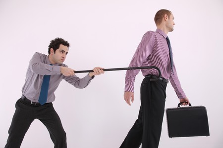 Businessman trying to pull another businessman with a caneの写真素材