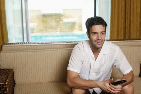 Man with remote control watching televisionの写真素材