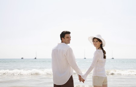 Man and woman holding hands on beachの写真素材