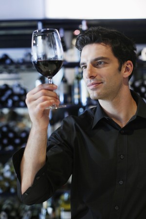 Man inspecting a glass of red wineの写真素材