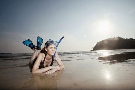 Man with scuba mask lying forward on the beachの写真素材