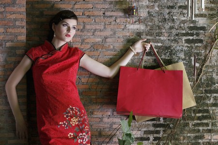 Woman in cheongsam carrying shopping bagsの写真素材