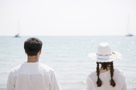 Man and woman enjoying the sea view from the beachの写真素材
