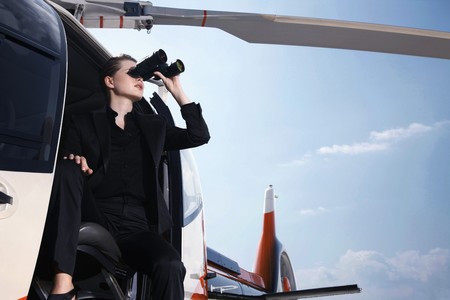 Businesswoman looking through binoculars from helicopterの写真素材