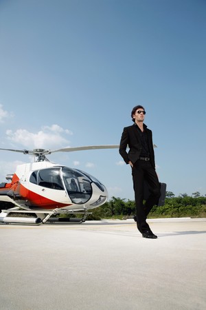 Businessman holding briefcase with helicopter at helipadの写真素材