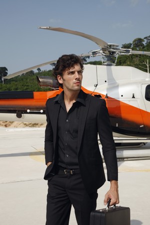 Businessman holding briefcase with helicopter in the backgroundの写真素材