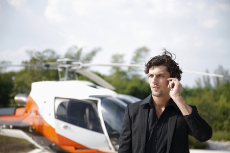 Businessman talking on the phone with helicopter in the backgroundの写真素材