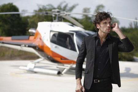 Businessman talking on the phone with helicopter in the backgroundの写真素材