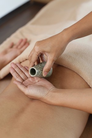 Massage therapist applying therapeutic oil on manの写真素材