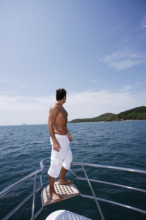 Man standing on the tip of yachtの写真素材