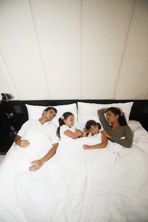 Family sleeping together on bedの写真素材