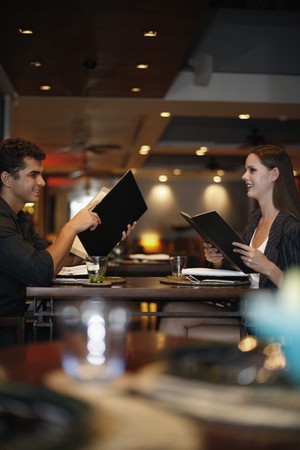 Man and woman reading menu in restaurantの写真素材