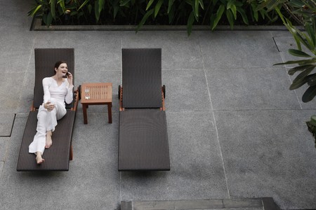 Woman talking on the phone while relaxing on lounge chairの写真素材