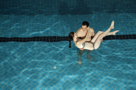 Man carrying woman in swimming pool