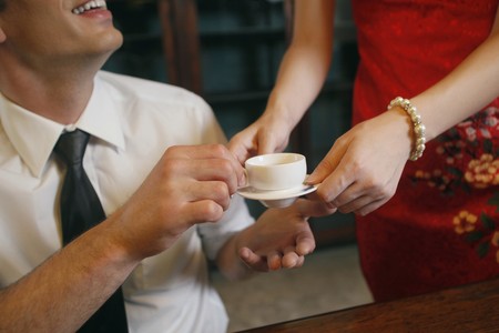 Woman serving businessman with a cup of teaの写真素材