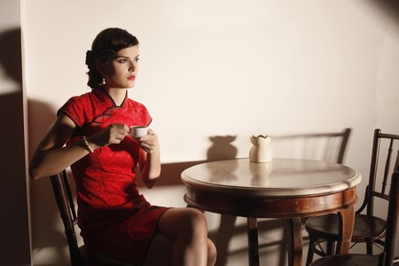 Woman in cheongsam with a cup of teaの写真素材